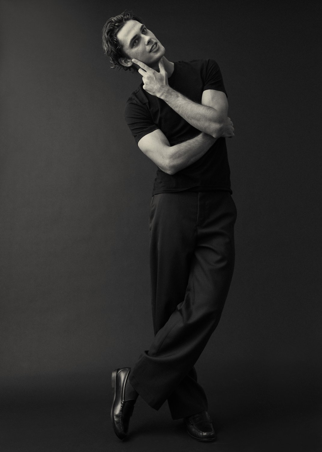 Black-and-white full-length studio portrait of Ivan in a black tee and trousers